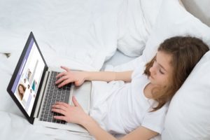 Girl Chatting On Social Networking Site With Laptop In Bedroom